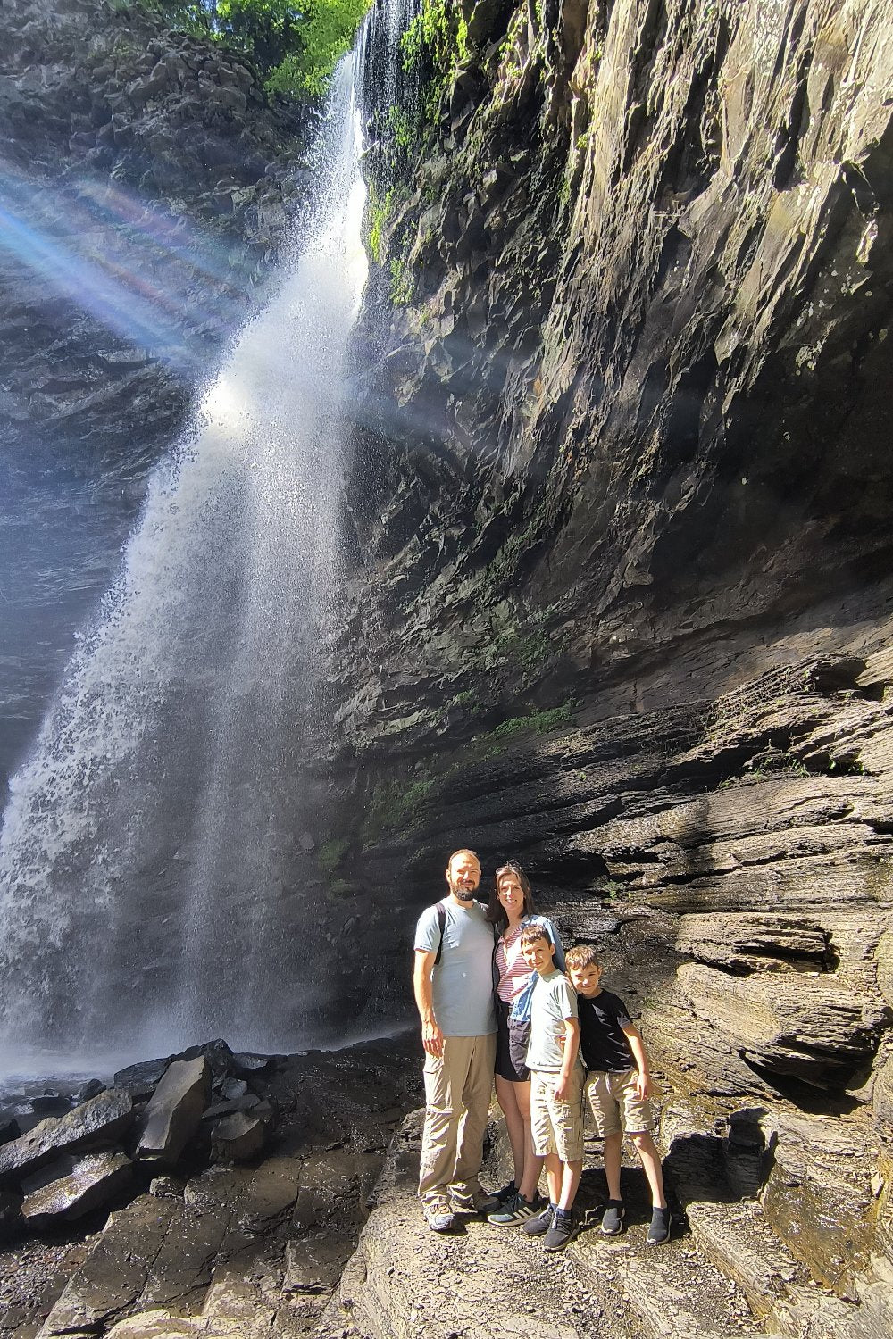 Family photo of the owners of sweet arrival shop standing beside a big waterfall on a hike. 